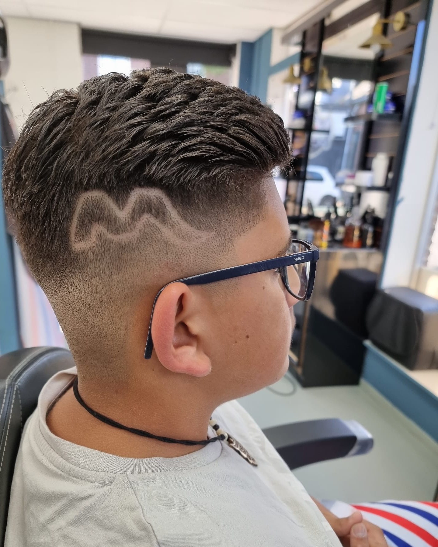 Jongen met een fade en een golvend lijntje in de zijkant geschoren