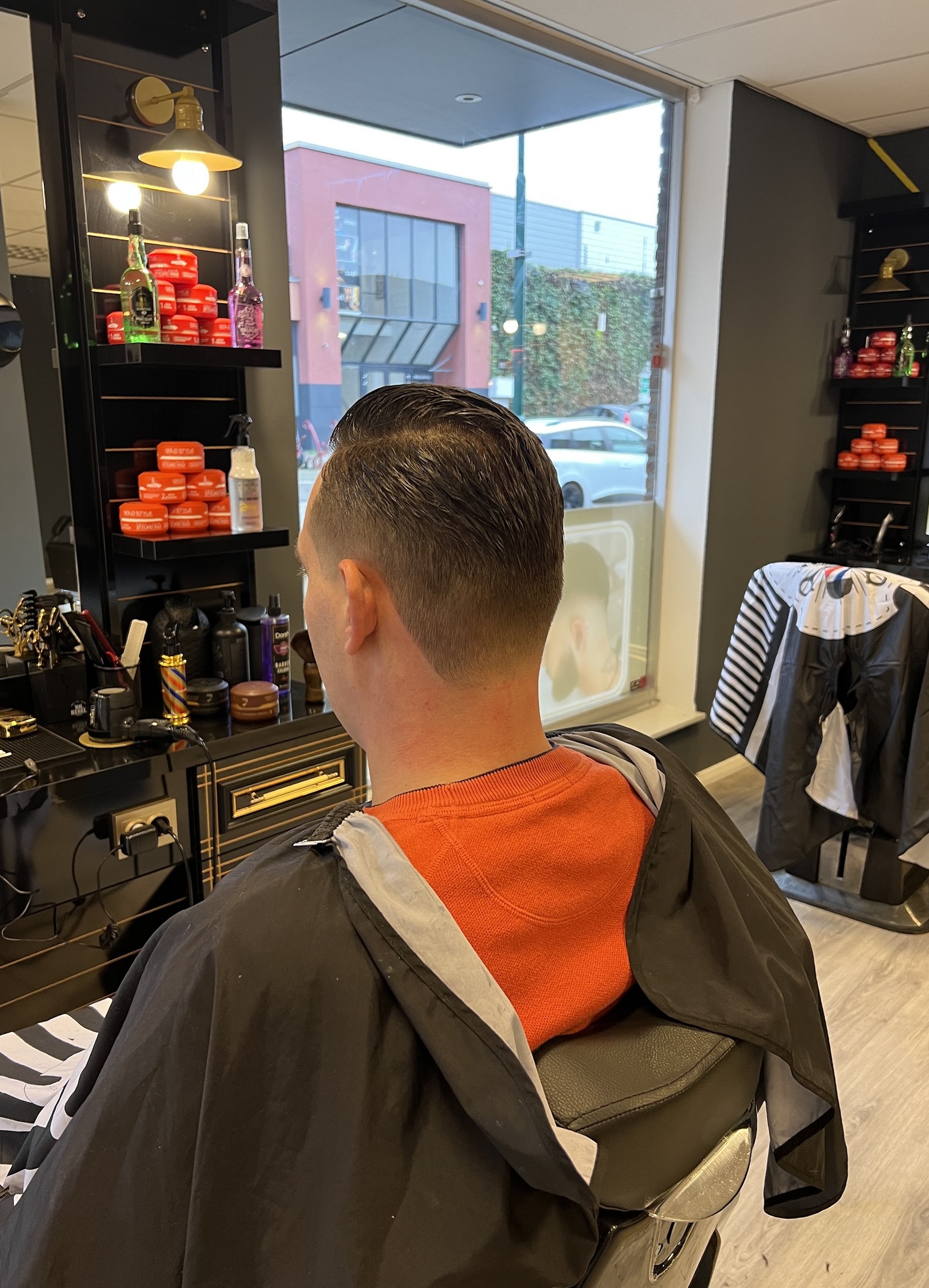Klant in de stoel met zicht op het raam, de kasten met producten ernaast