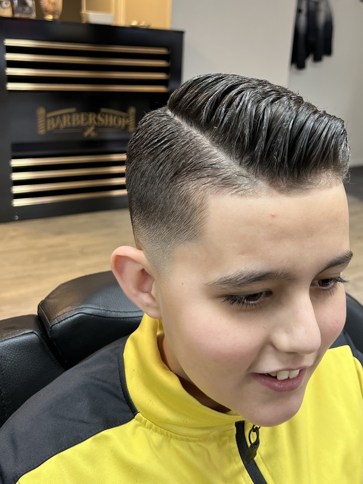 Jongen in de stoel met een strakke scheiding, voor de zwarte balie met gouden lijnen