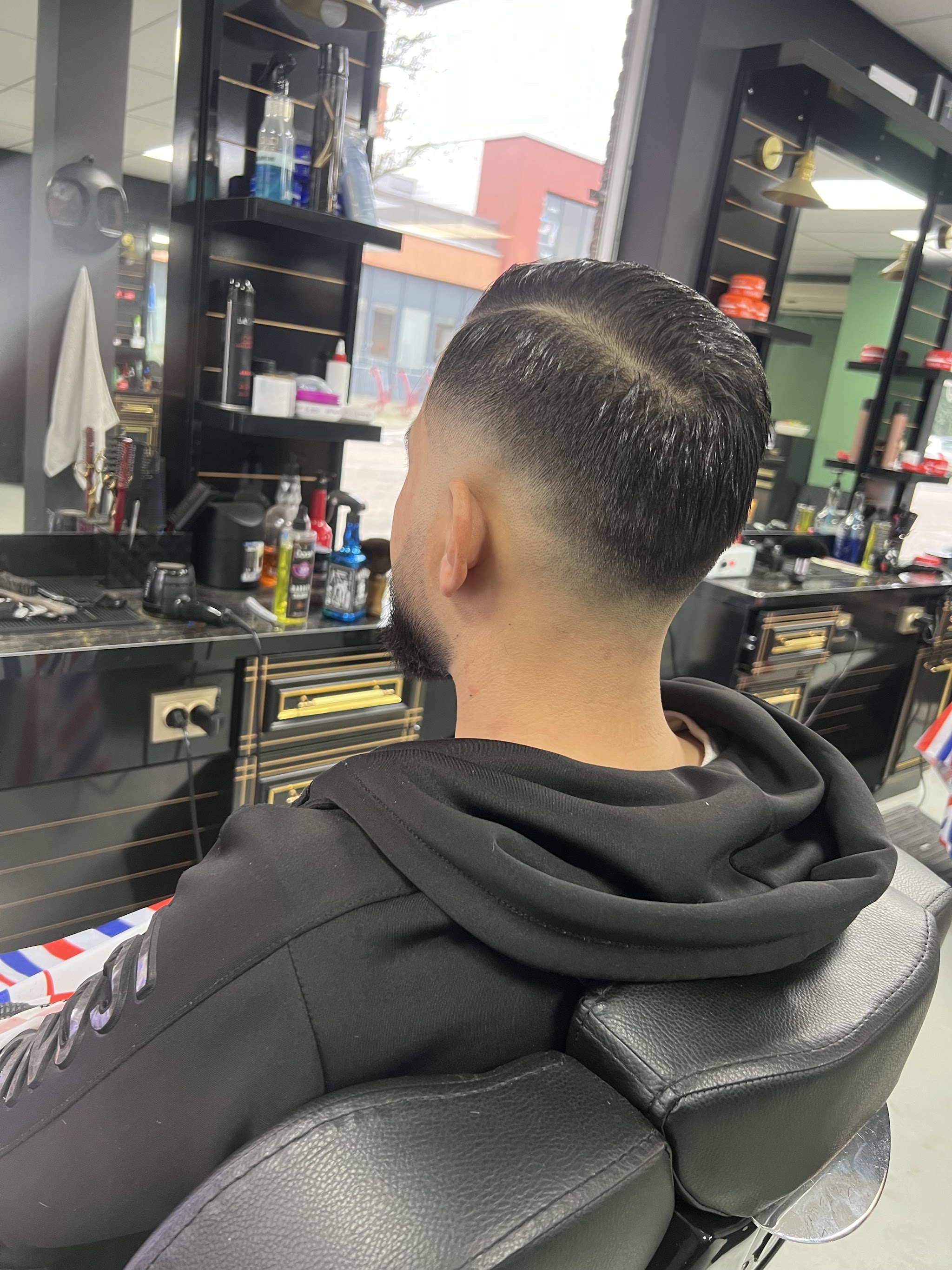Fade met een strakke scheiding, van achteren gezien in de stoel bij Kapsalon Adam